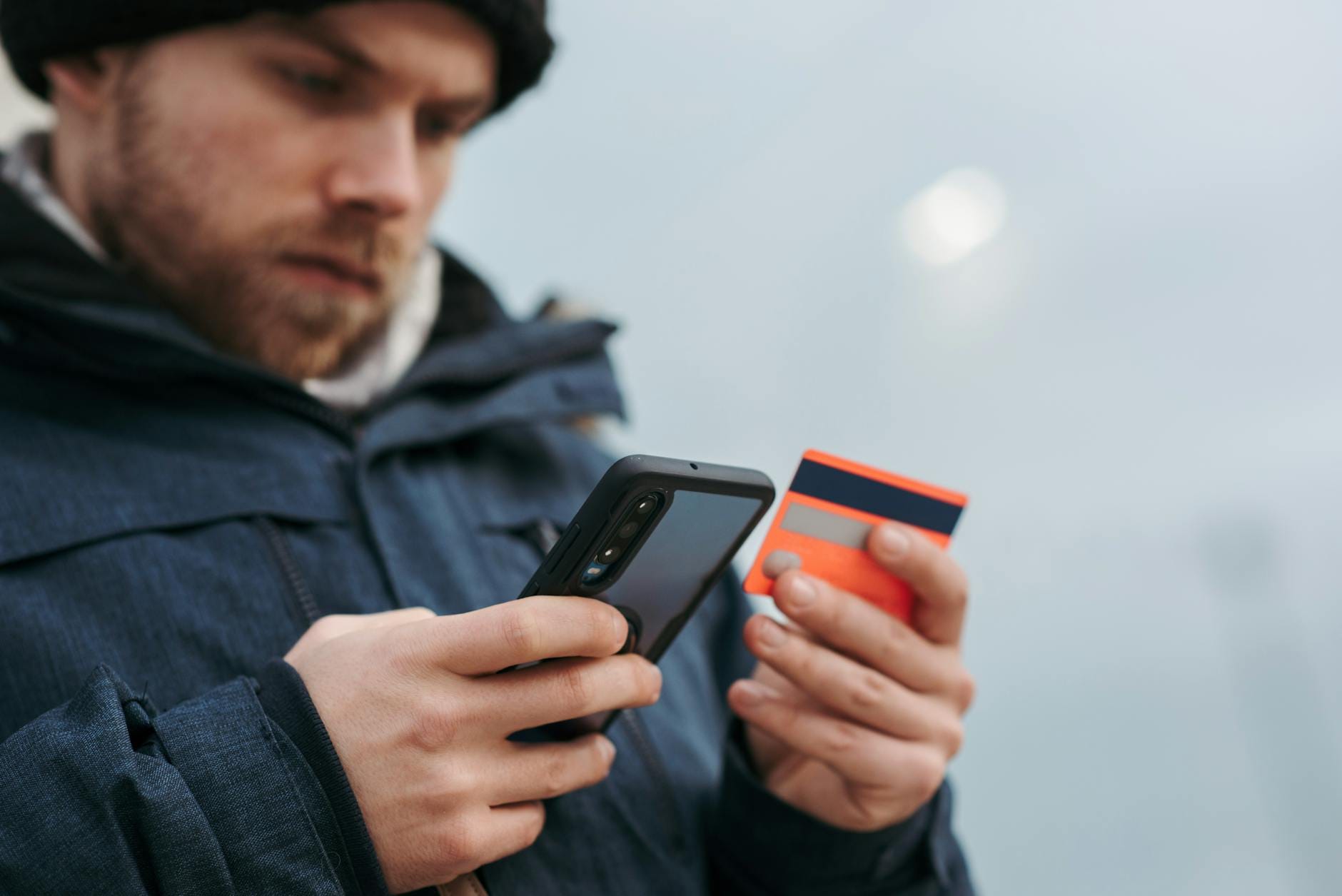 Mężczyzna wpisuje dane karty płatniczej w smartfonie podczas zakupu online
