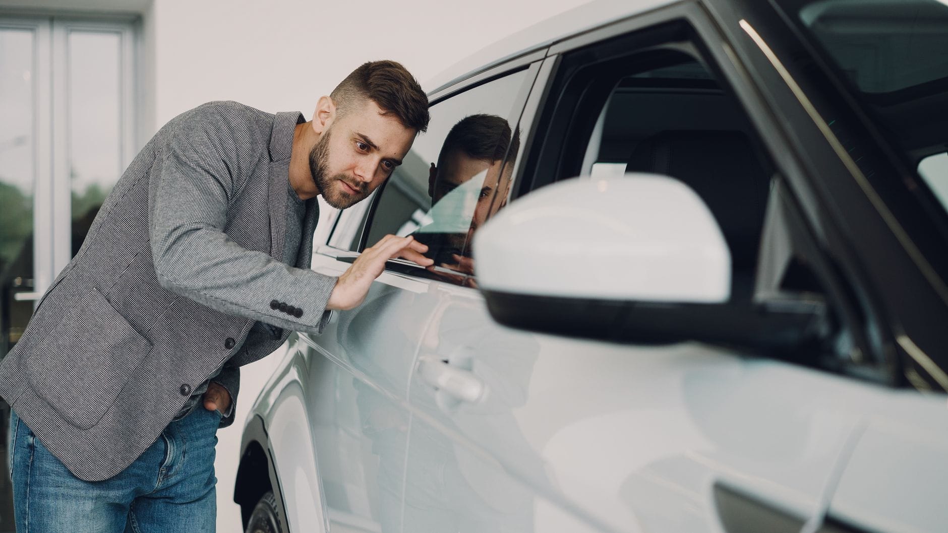 Mężczyzna ogląda dokładnie biały samochód w salonie dealerskim